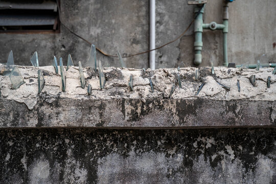 Concrete wall topped with glass shards for security in an urban setting.