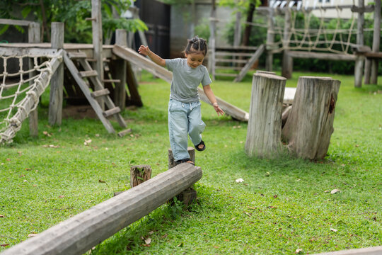 preschool child girl walking and balancing on wooden beam in outdoor Playground