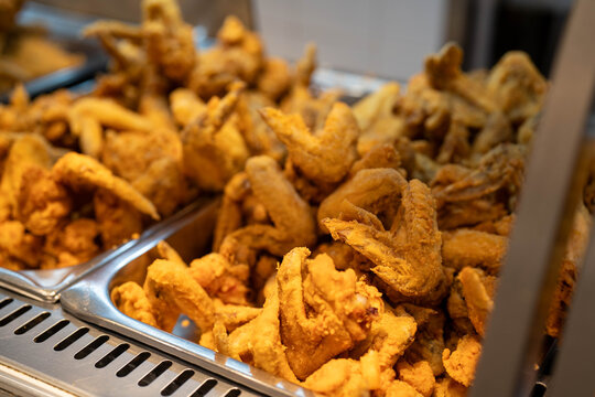 Golden crispy fried chicken wings piled high in a stainless steel food tray.