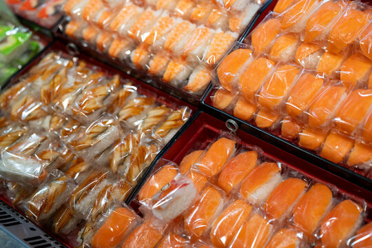 A colorful array of sushi varieties neatly packaged and displayed in a market.