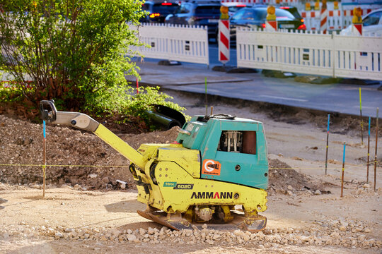Ammann APH 6020 reversible vibratory plate compactor at a road construction site.