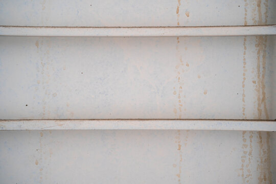 Close-up of weathered metal surface with horizontal lines and subtle water stains.