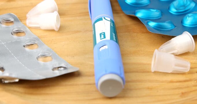 Semaglutide GLP-1 injection pen with used hypodermic needles and empty pill blisters rotating for diabetes and obesity treatments.