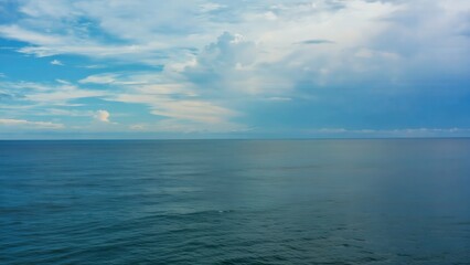 Fototapeta premium Vast open ocean under soft cloudy sky with deep focus, showcasing tranquil water surface and gentle waves, creating a serene coastal atmosphere in a wide shot