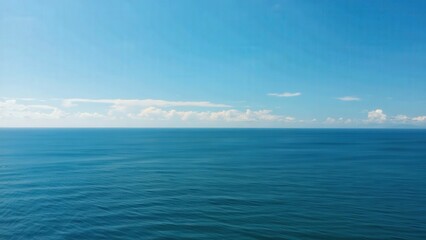 Fototapeta premium Calm ocean horizon with gentle waves under a clear blue sky, showcasing a slow dolly movement across the tranquil water surface and distant clouds