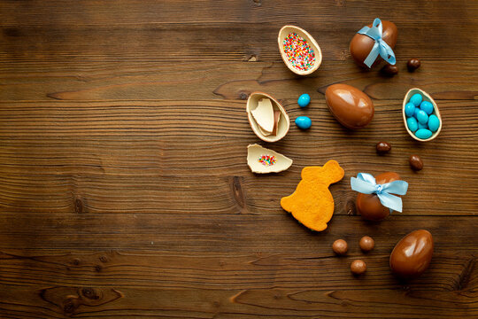 Top view of lots of chocolate Easter eggs with blue ribbon on a wooden background