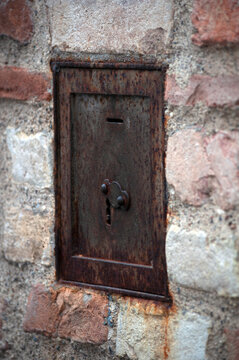 antique iron piggy bank in a brick wall with a coin hole and keyhole