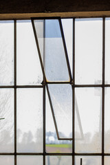 Fototapeta premium View through old window with blurred frame towards trees and green field