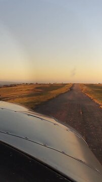 Pilot View from Small Aircraft on Final Approach to Rural Airstrip at Golden Hour with Scenic Countryside Landscape. General Aviation Plane Landing on Remote Runway at Sunset