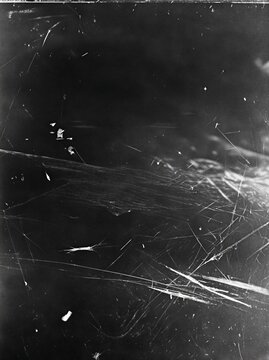A dark, vintage black and white film texture featuring heavy scratches, dust particles, and scuff marks for grunge overlays.