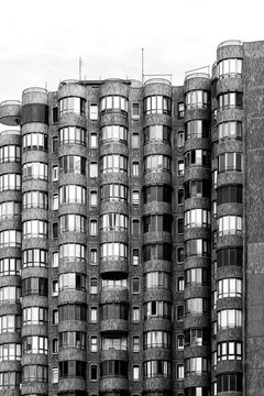 Rounded windows fill a black and white facade, where architecture, building pattern and exterior geometry create a compact urban wall