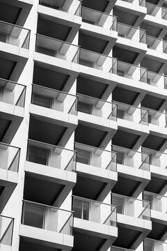 Balcony shadows repeat through black and white architecture, making windows, facade geometry and building exterior pattern read as rhythm