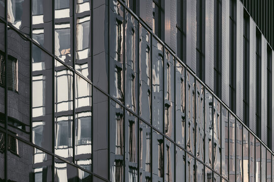 Reflected facade lines stretch through glass windows, where urban architecture and building surfaces form abstract exterior geometry in shadow