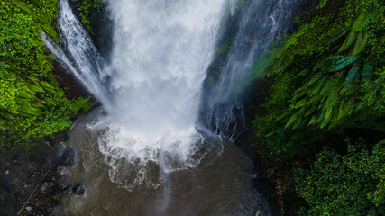 Aerial view of Beautiful Gomblang Waterfall in the middle of forest, Java, Indonesia. Dense waterfall with lush vegetation  © katakaneh