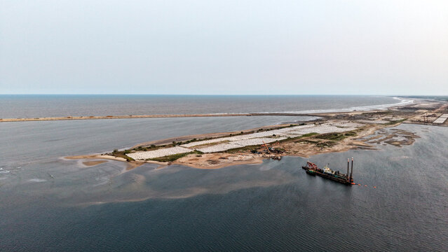 Aerial view of new port construction site with sand dredging operations