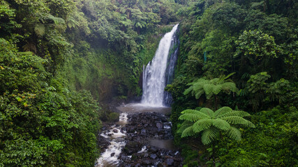 Aerial view of Beautiful Gomblang Waterfall in the middle of forest, Java, Indonesia. Dense waterfall with lush vegetation  © katakaneh