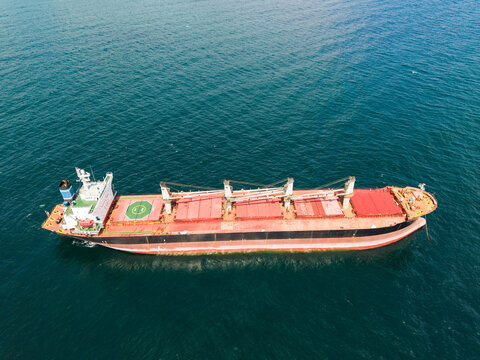 Aerial view of a large bulk carrier cargo ship with red deck and cranes navigating the deep blue waters of the Black Sea off Fichoza Beach near Varna, Varna, Bulgaria.