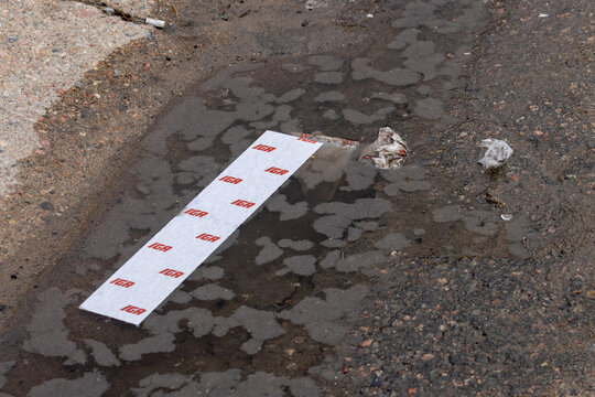 La Tuque, Canada, 10 May 2026 : A discarded IGA grocery store receipt lies in a puddle on the ground next to other litter.