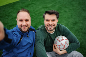 Happy friends taking selfie on soccer field with ball © Jelena