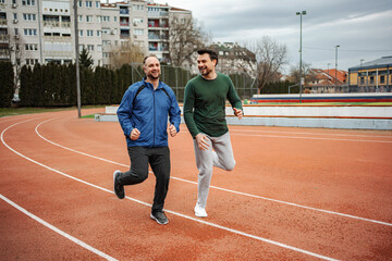 Fototapeta premium Two men friends jogging on running track