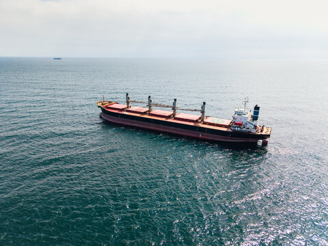 Aerial view of a large bulk carrier cargo ship with red and black hull anchored in the calm blue waters of the Black Sea near Varna, Varna, Bulgaria.