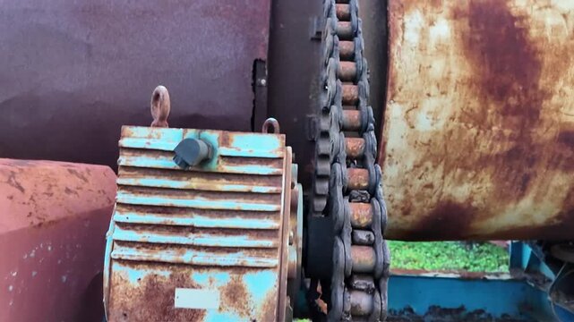 A close-up video of a rusty old machine with a chain and gears
