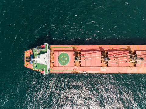 Aerial view of a large bulk carrier ship with a red deck and green helipad sailing on the dark blue waters of the Black Sea near Varna, Varna, Bulgaria.