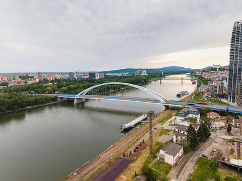Aerial view of Apollo Bridge spanning the Danube River with the city skyline and Bratislava Castle under a cloudy sky Bratislava, Bratislava Region, Slovakia.