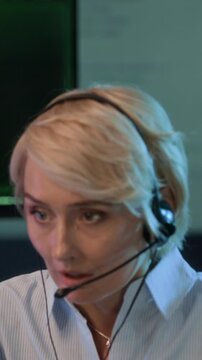 Vertical shot of emergency operator wearing headset while reporting about cyberattack working in control center with computers