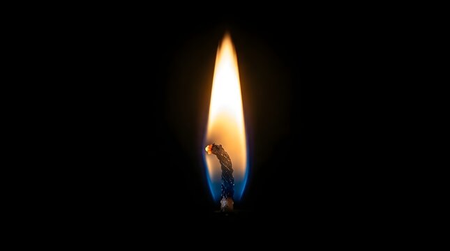 A closeup view of a candle flame burning brightly in the dark with a warm glow and blue undertones