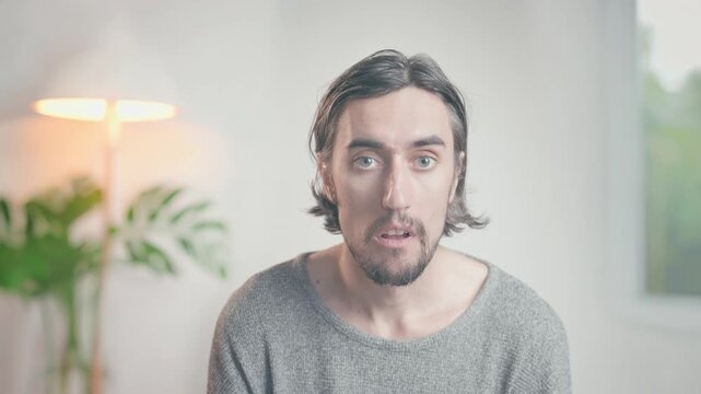 Lonely funny guy close-up of a young man with dark hair and beard indoors in warm natural light showing subtle expressions of surprise, curiosity, thoughtfulness, mild amusement in a calm