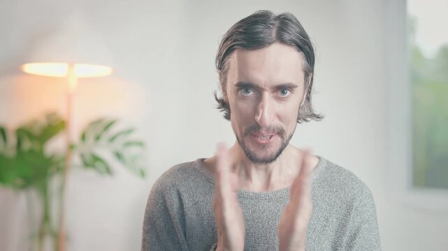 Crazy applause craving ovations of a lonely funny guy indoors in a warm cozy setting with soft lighting, clapping hands from calm prayer pose to playful smile while maintaining eye contact