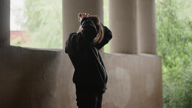 Lady repairs hair. Silent female beneath falling rain. Outlined figure remains strong during turbulent weather. Woman adjusting her hair quietly as storm surrounds her with fierce winds