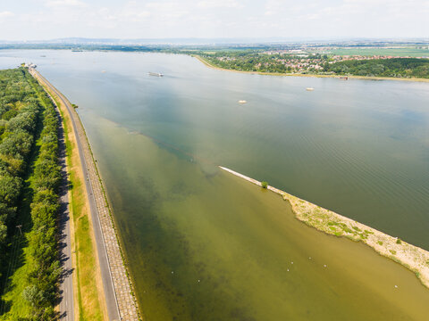 Aerial view of the Danube river with a long embankment, a small sandbar, and a cargo ship in the distance near Bratislava, Bratislava Region, Slovakia.