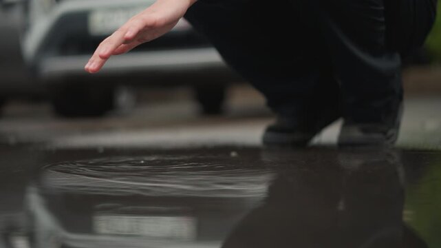 Female carefully inspects water surface. Caucasian woman thoroughly looks at reflected image in pond water. Woman of Caucasian descent meticulously observes mirrorlike surface of small pond