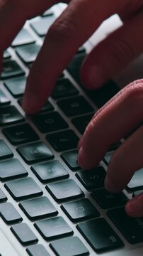 Side close-up of an unrecognizable freelancer typing on a laptop on their lap.