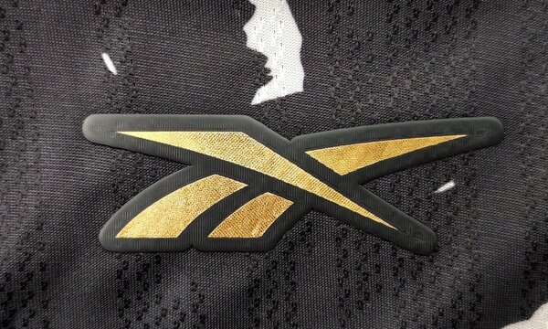 Closeup view of the golden Reebok logo embroidered on the 2024&ndash;2025 fourth kit jersey of Botafogo de Futebol e Regatas.