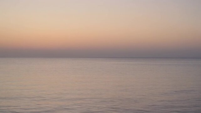 Calm ocean waves gently rolling towards the sandy shore during a beautiful peaceful sunset in this cinematic video clip
