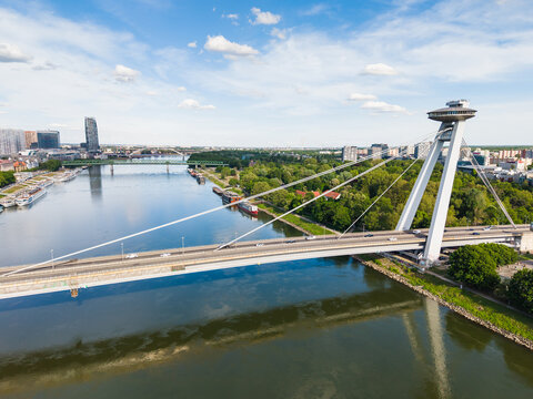 Aerial view of the Most SNP bridge with its iconic UFO observation deck spanning the Danube river under a blue sky in Bratislava, Bratislava Region, Slovakia.