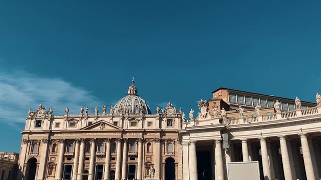 Panning shot st peters basilica facade and colonnade at vatican city square under clear blue sky Italy Rome.