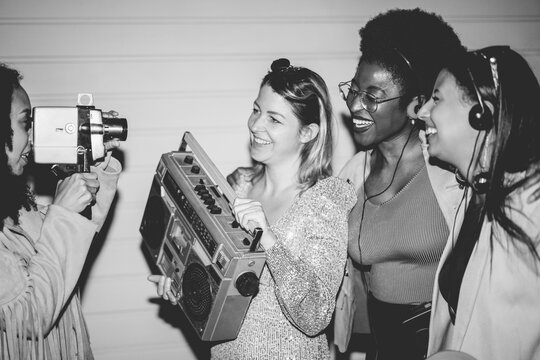 Group of multiracial girls having fun together dancing listening music while taking video with a vintage super 8 camera outdoor - Party, nightlife and people lifestyle concept 