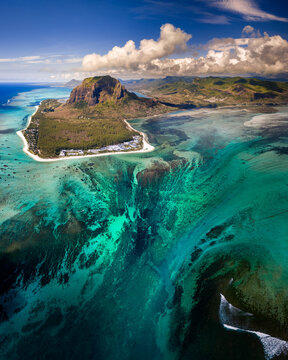Aerial view of Le Morne Brabant mountain and the famous underwater waterfall illusion surrounded by turquoise coral reefs and white sand beaches Mauritius, Moka District, Mauritius.