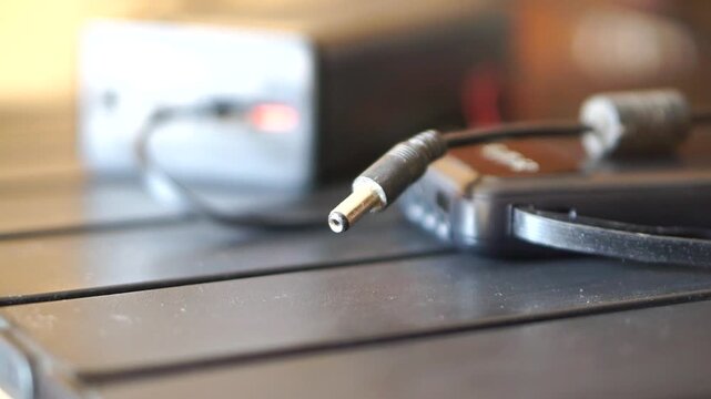 DC charger connector placed beside a modern smartphone, presenting the concept of electronic accessories and portable power sources.