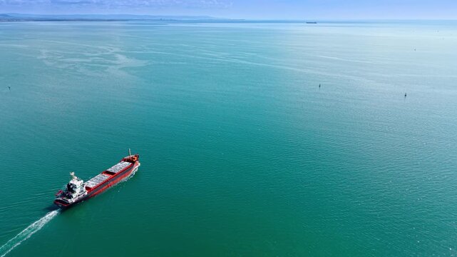Bulk carrier moving by the vast turquoise waterscape. General cargo ship goes on a voyage. Aerial view.