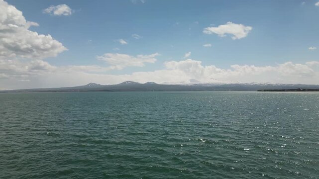 The Lake Sevan, the largest lake in Armenia, surrounded by mountains and clouds. Clear blue water, rugged shoreline, and vast high-altitude landscape captured from a drone in the Caucasus region.