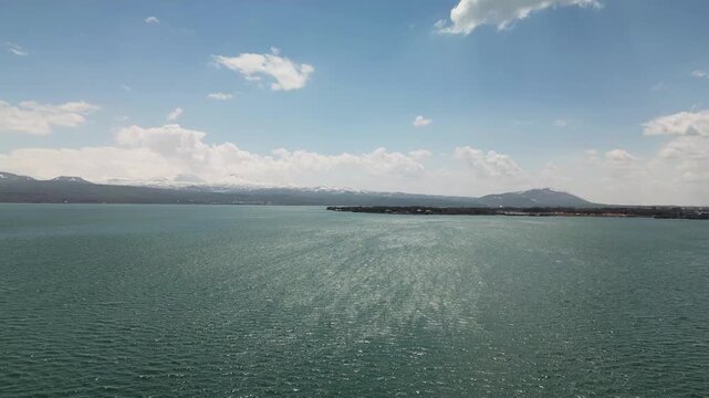 The Lake Sevan, the largest lake in Armenia, surrounded by mountains and clouds. Clear blue water, rugged shoreline, and vast high-altitude landscape captured from a drone in the Caucasus region.