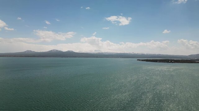 The Lake Sevan, the largest lake in Armenia, surrounded by mountains and clouds. Clear blue water, rugged shoreline, and vast high-altitude landscape captured from a drone in the Caucasus region.