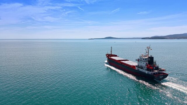 Empty cargo ship in a voyage. Following a carrier bulk going by the calm waterscape.