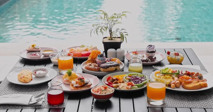 Breakfast spread featuring eggs benedict and pastries resting on table, poolside luxury resort setting, travel and hospitality marketing material