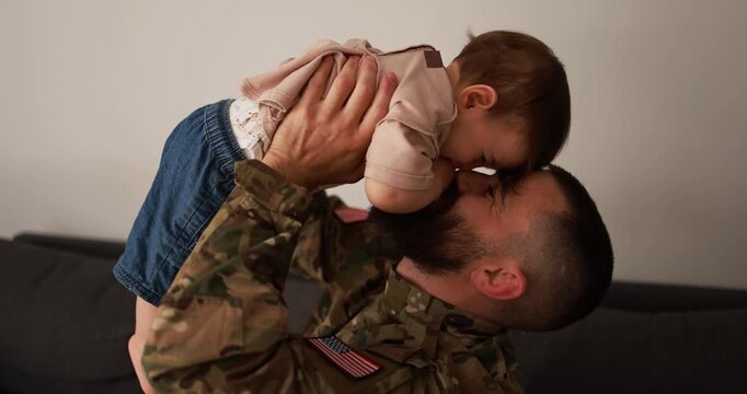 Male american soldier in military uniform having tender moment with his little son at home - Emotional military homecoming and family concept